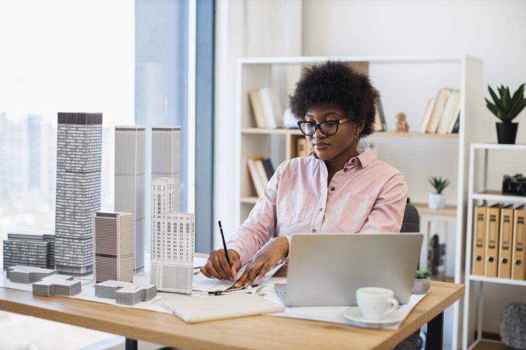 African woman architect planning modern city with building models